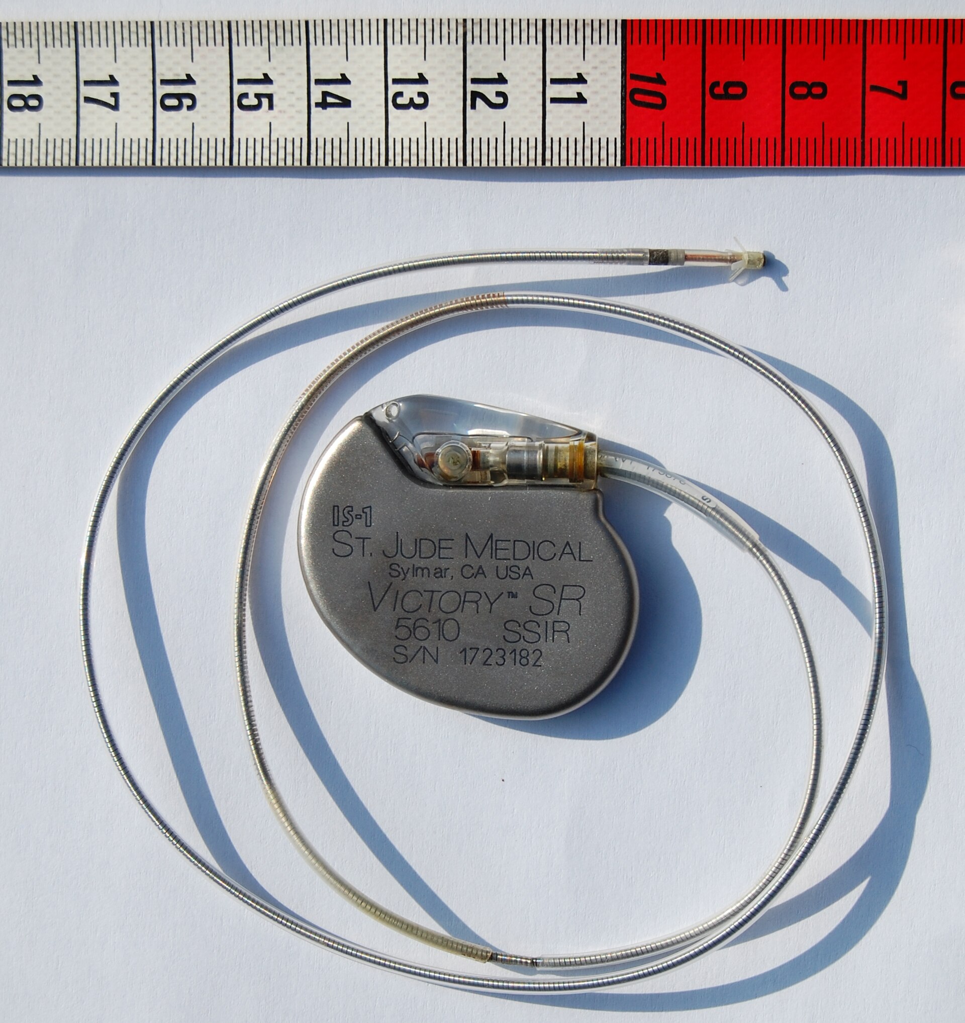 An implantable cardiac pacemaker beside a ruler